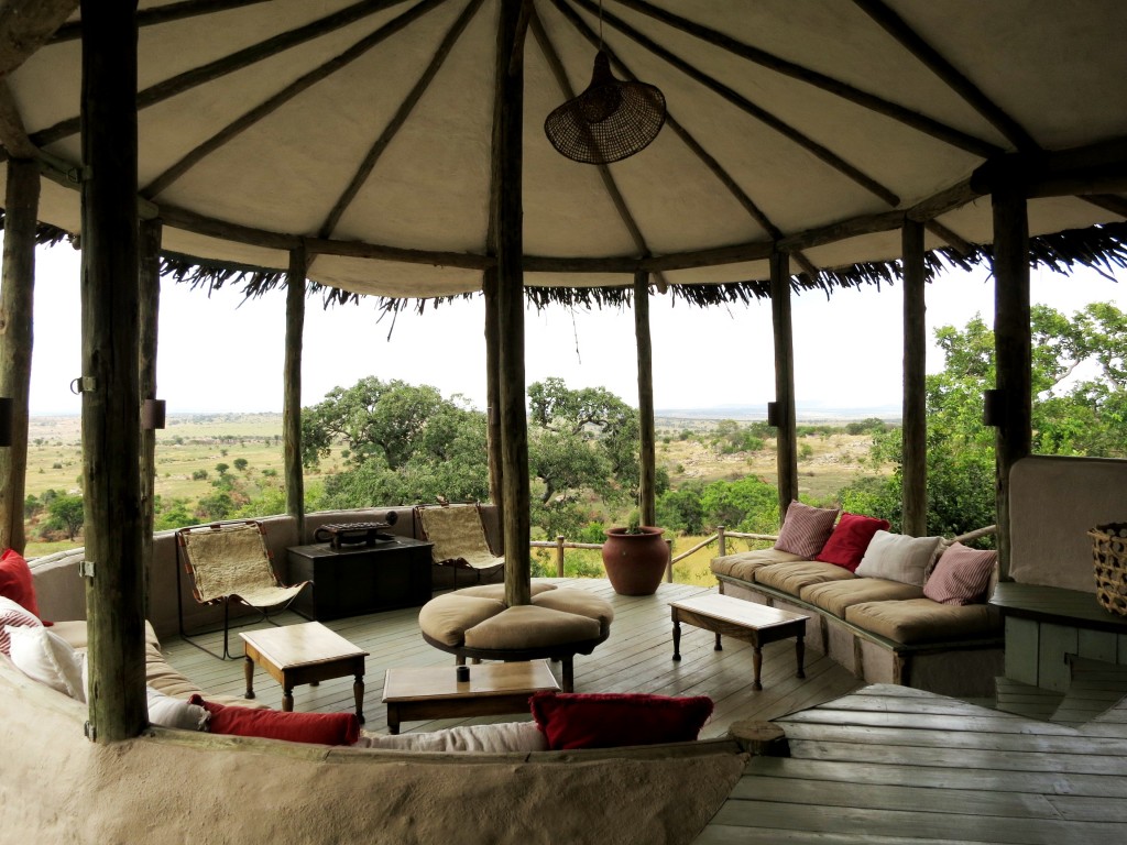 The reception area at Lamai Serengeti is decorated with colorful throw pillows and looks out to the rolling hills of Kenya