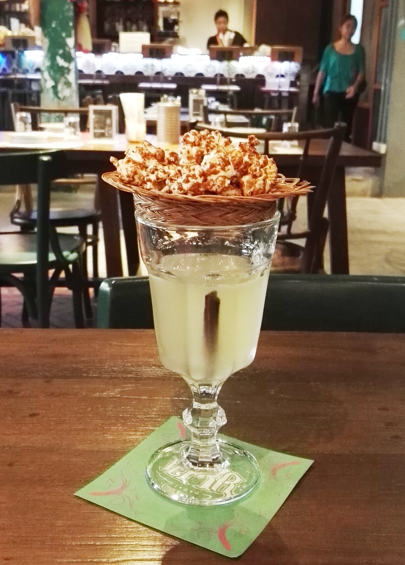 GMtini made with a Thai corn spirit infused with lime, Thai basil and cinnamon and topped with popcorn-- your drink's automatic bar chow on a plate.