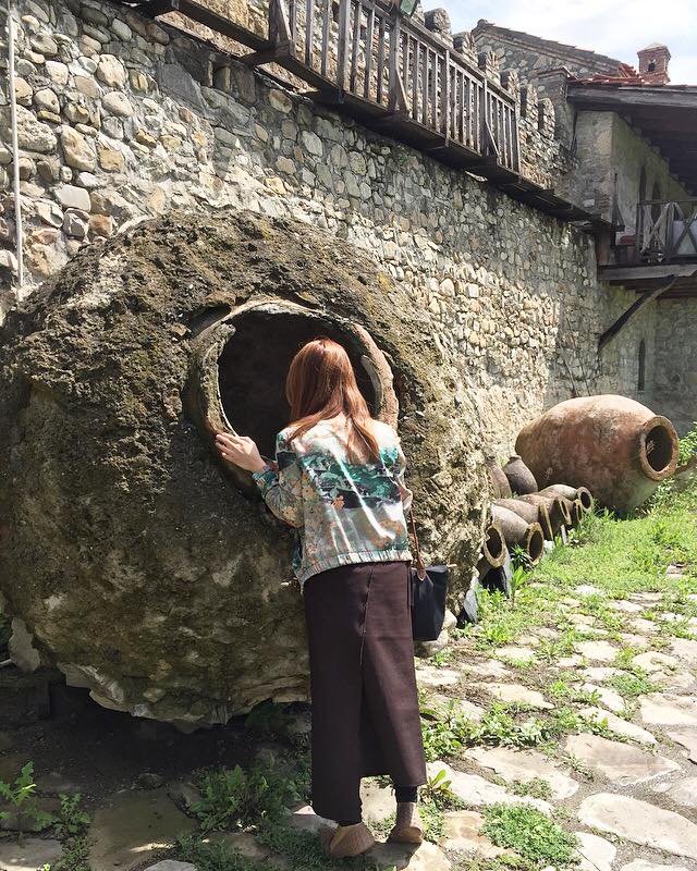 The qvervi was how Georgians made wine 8,000 years ago-- and still do today! Grape juice is fermented with the grape skin in this clay pot vessel (the famous qvervi!⚱⚱⚱) buried under the earth. Just to show you how massive the qvevri is, 5 ft.0" tall me could fall in and drown in the wine!😵🍷 PS Since Alaverdi Winery is a monastery, all women are required to be covered up. They provide you the brown cloth (that I'm wearing) at the entrance. (Photo by Juliana Dever)